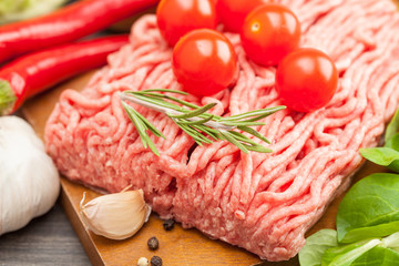 raw minced meat with vegetables on wooden board, selective focus