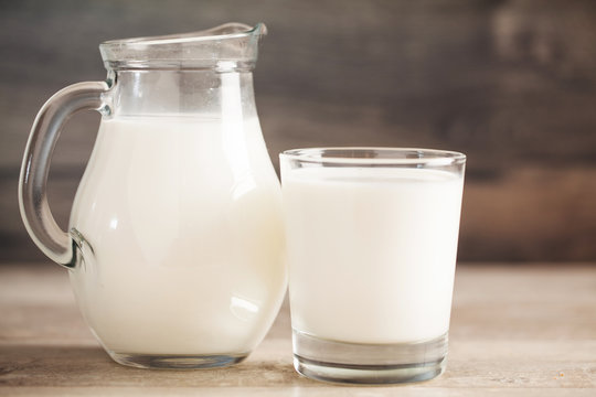 fresh milk in glass jug and glass on wooden background. Selective focus.