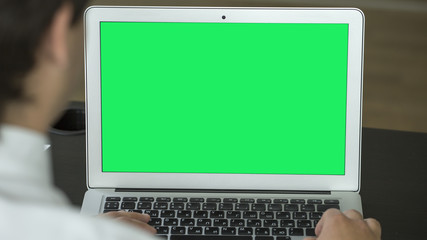 Man working on laptop in the office. Green screen.