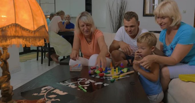 Little boy, father and two grandmothers spending time together at home. They playing with construction kits
