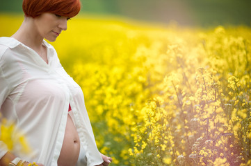 Kobieta w ciąży na plantacji rzepaku