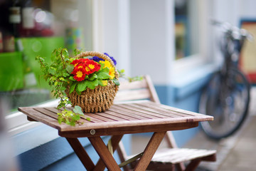 Beautiful flowers blossoming in a basket on the table in an outdoor cafe