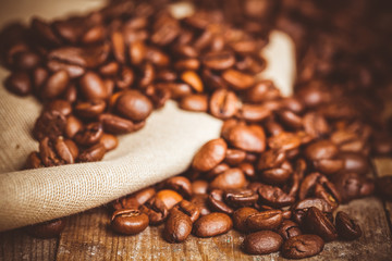 Toned photo of coffee beans on wood background. Selective focus.