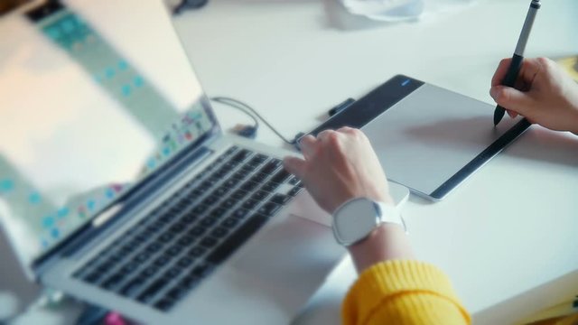 Graphic designer working with drawing tablet with pen on white surface