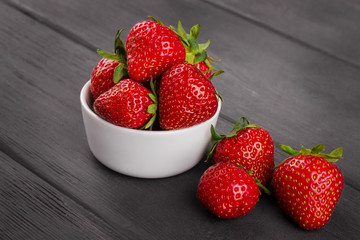 bowl filled with  fresh ripe red strawberries on wooden table to