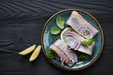 Deurstickers Top view of fresh herring fillet on a black wooden background © Nickola_Che