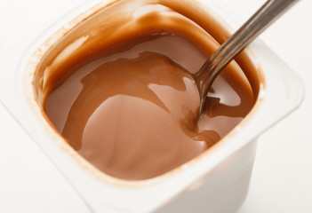 Open yogurt in pot with metal spoon