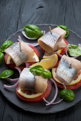 Canapes with herring, lemon, tomatoes, onion and basil, close-up