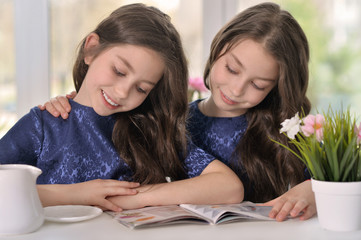 little twin girls reading a magazine