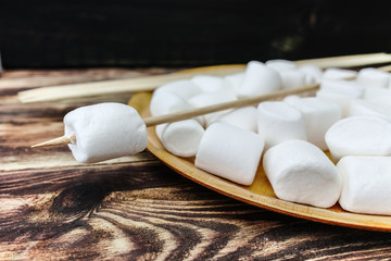 Fluffy white marshmallow in wooden bowl on old wooden table