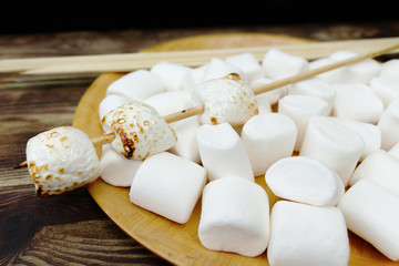 Fototapeta na wymiar Fluffy white marshmallow in wooden bowl on old wooden table