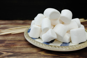 Fluffy white marshmallow in wooden bowl on old wooden table