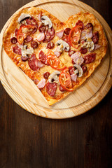 Pizza heart shape on dark wooden background top view