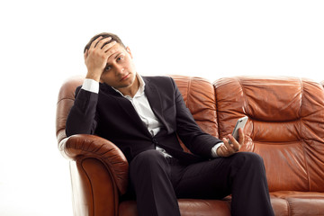 Businessman with phone .on the couch holding head