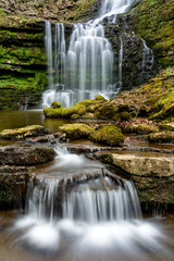 Obraz premium Flowing waterfall in remote Yorkshire woodland with small cascade. 