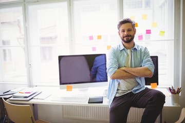 Fototapeta premium Portrait of businessman sitting on desk in creative office