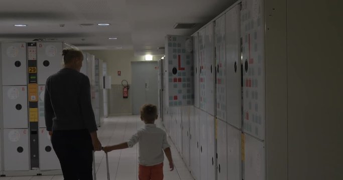 Mother and child coming to luggage room and leaving suitcase in the locker