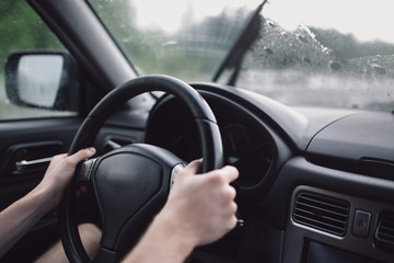 Drive car in rain. Hands on steering wheel