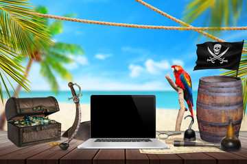 Computer on pirate table with treasure, map, rum, compass, knife. Palm tree, beach and sea in...