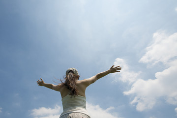 青空に向かって手を広げる女性