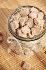 Brown cane sugar cubes in the glass jar, closeup