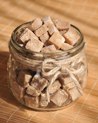 Brown cane sugar cubes in the glass jar, closeup
