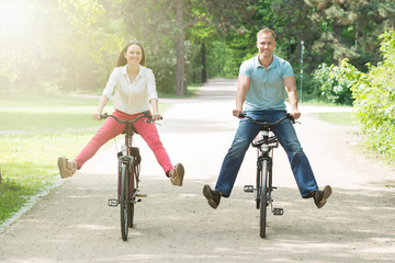 Happy Couple Riding Bicycle In Park