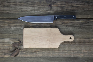 Cutting board with knife on wooden table.