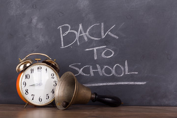 Bell and alarm clock against a blackboard