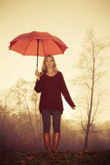 Fashion woman with umbrella relaxing in fall park.
