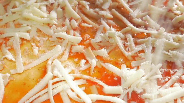 Cheese adding on pizza in 4K 3840X2160 UHD video - Cheese sprinkling over pizza base 4k 2160p UHD footage