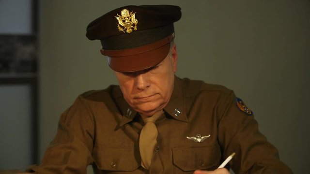 tilt from WWII captian to radio on table while he goes over recon photos