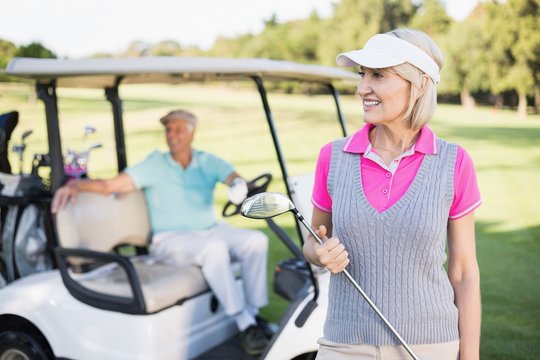 Happy mature woman holding golf club