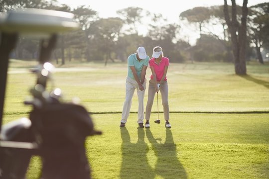 Full length of man teaching woman to play golf