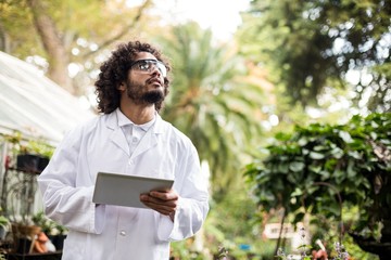 Male scientist inspecting plants at greenhouse