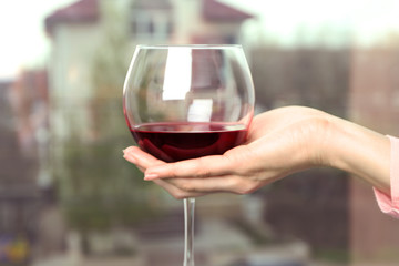 Woman holding glass of wine on blurred background