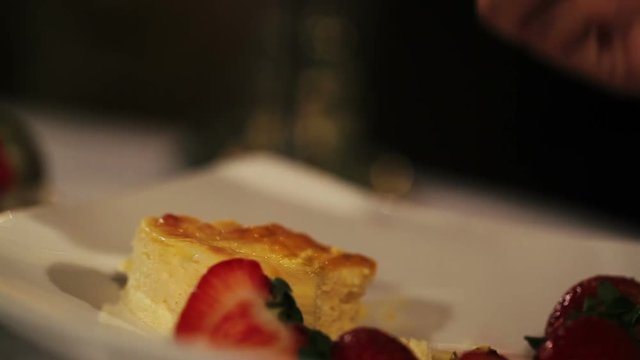 Woman take piece of dessert with strawberry by fork in restaurant. Dinner. Romantic