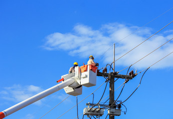 Electricians repairing wire of the power line on basket hydraulic lifting platform 