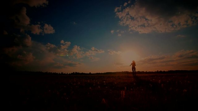 Young girl with outspread hands have fun at sunset in the field