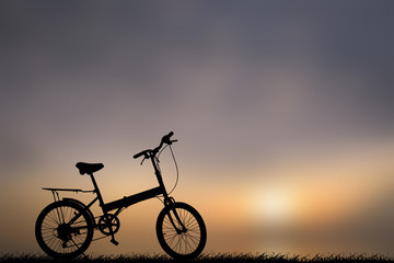 Fototapeta na wymiar Bike silhouette on the grass.Blurred background sunset