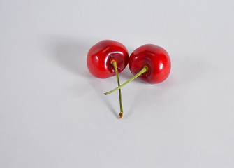 Two red cherries intertwine
