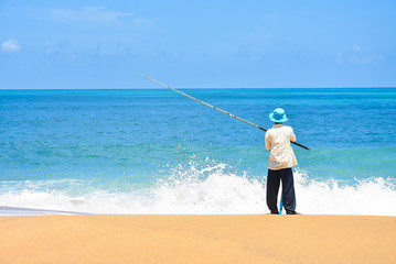 Fisherman fishing at the beach and wave of the sea, blue sky with fishing rod Fisherman fishing at the beautiful seascape Man fishing on Beach.