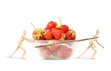 Two men drag a plastic box with ripe strawberries. Abstract image with wooden puppets