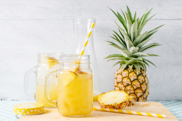 Pineapple slices and juice in glassware on wooden table