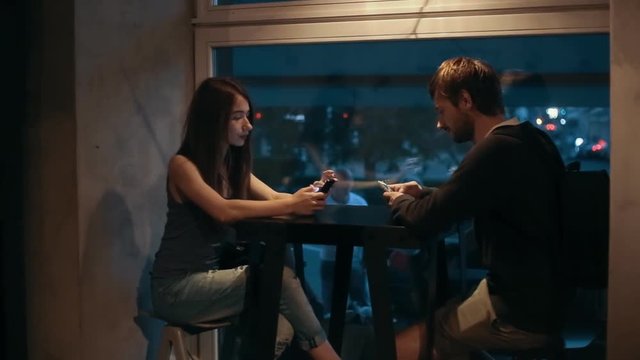 Couple Young Boy and Girl using the phone in cafe