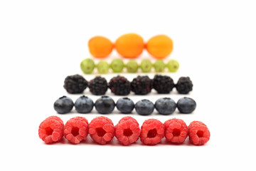different types of berries lie in rows on white background