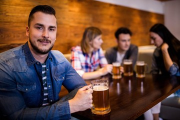 Man holding beer mug while friends in background