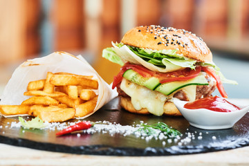 Fast food dinner of Burger, fries and a Cup of sauce, served on a stone Board