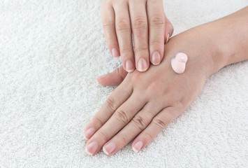 Female hands applaing a cream on fabric background