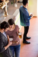 Woman showing cellphone to boyfriend while having beer 